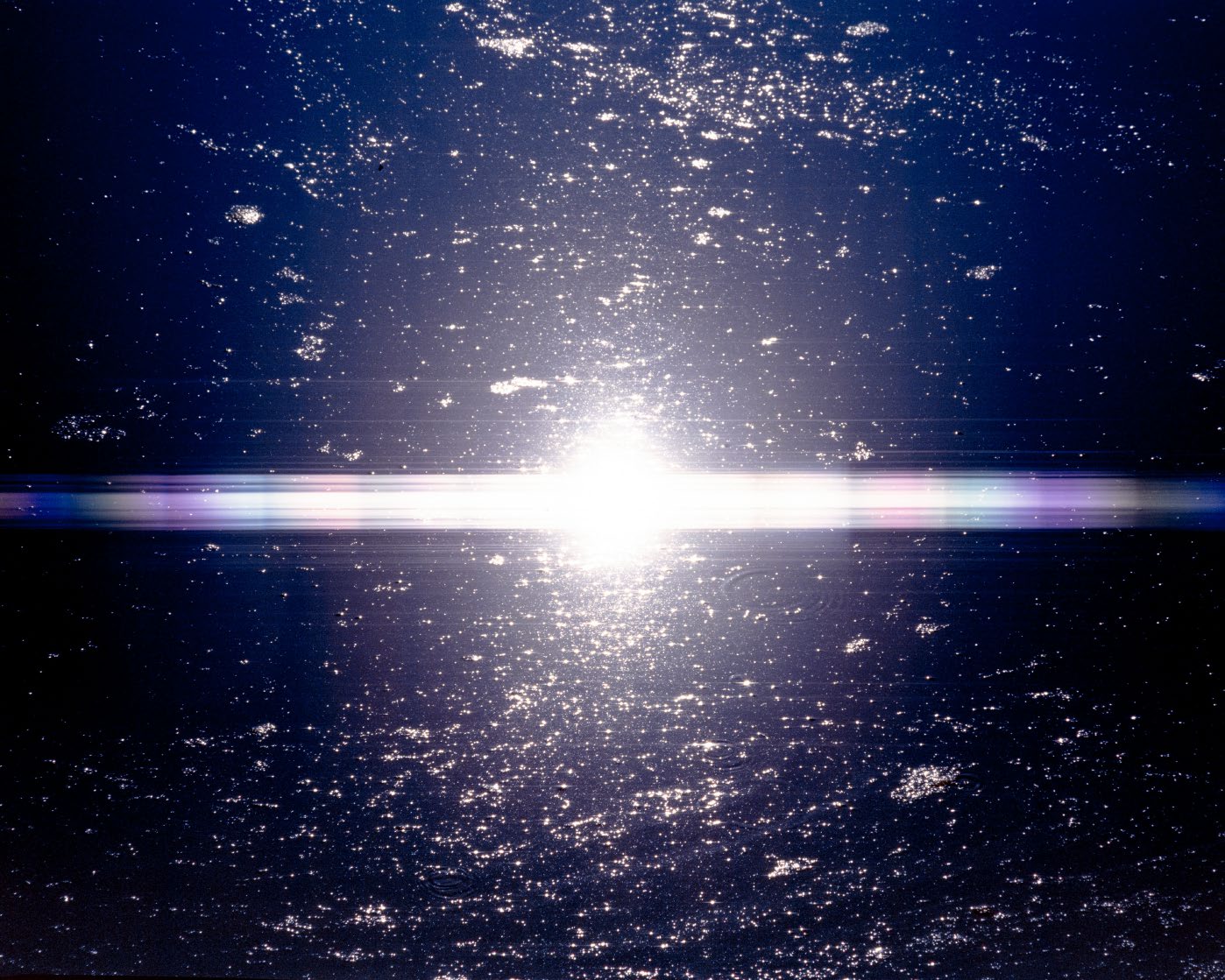 Luz intensa reflejada sobre superficie oscura formando un destello horizontal