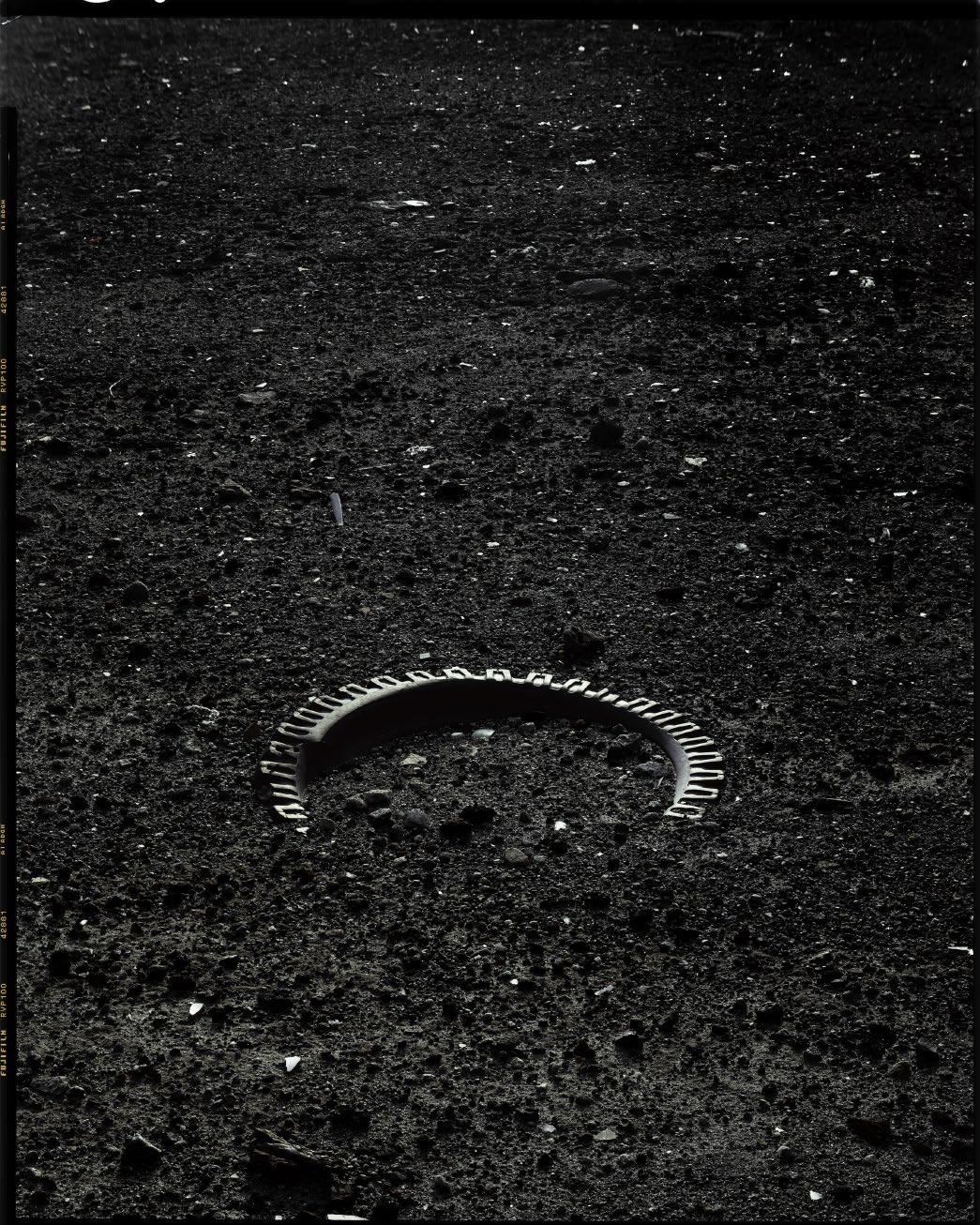 Fragmento de llanta sobre superficie rocosa oscura, blanco y negro