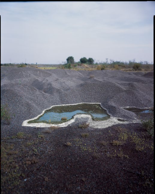 Charco de agua rodeado de terreno rocoso oscuro
