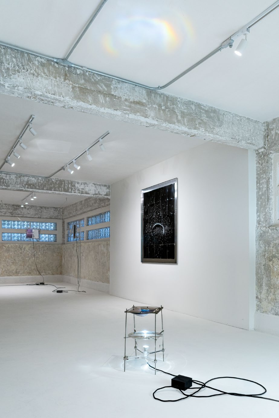 Vista de instalación con fotografía enmarcada y escultura lumínica en el suelo
