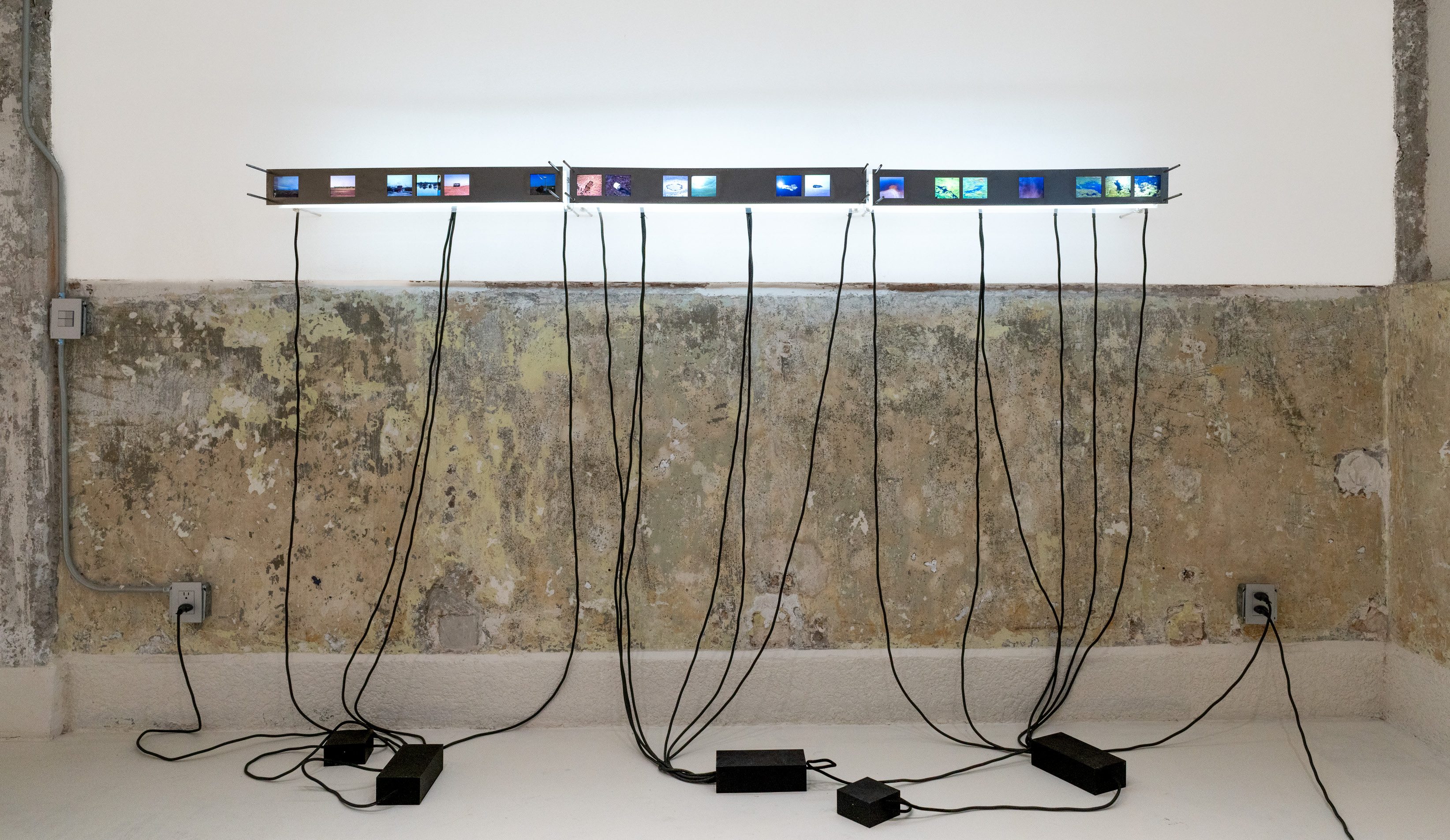 Serie de diapositivas montadas en una estructura horizontal iluminada, conectadas por cables