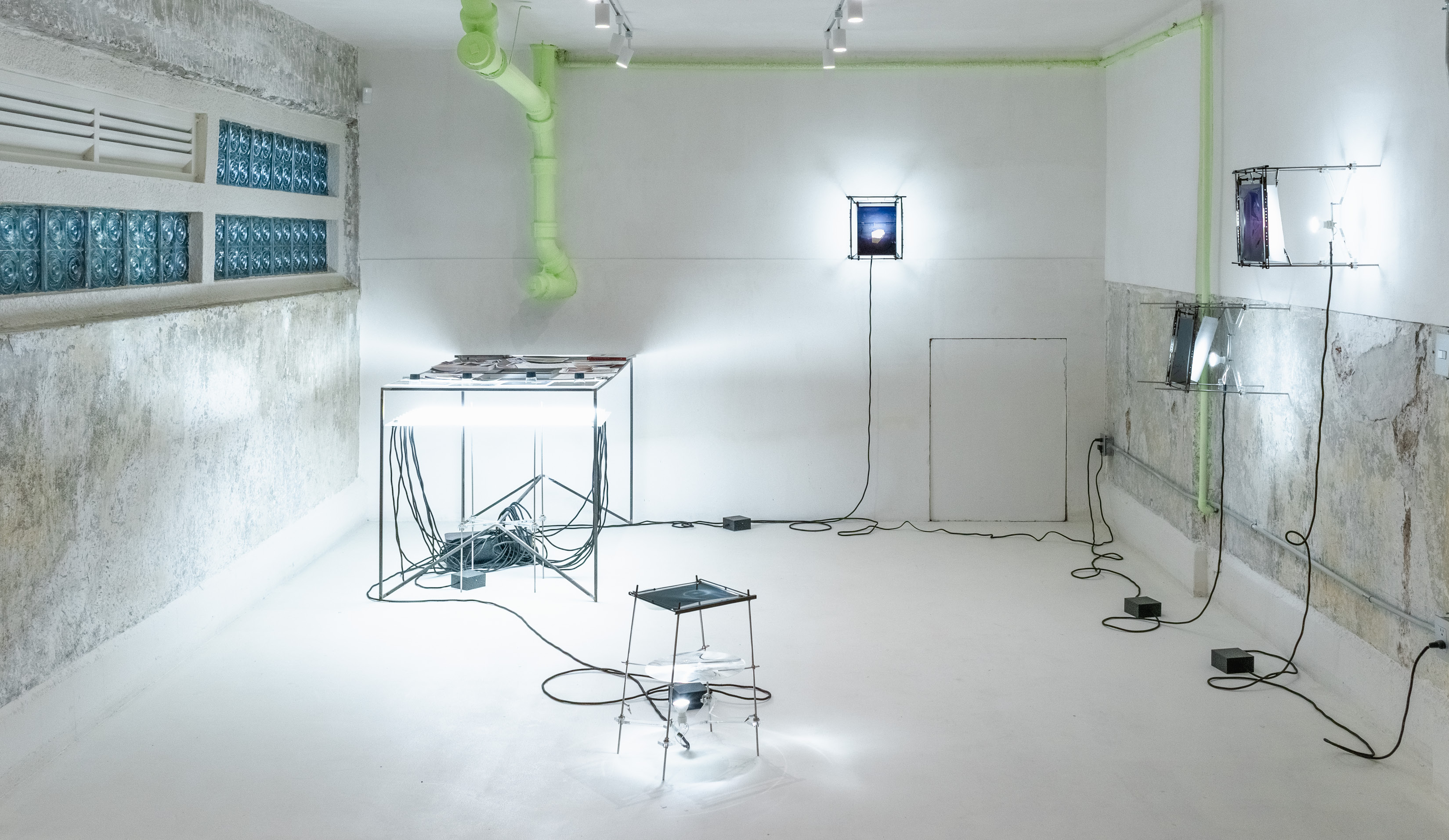 Vista de instalación con cajas de luz iluminadas y estructuras metálicas en sala blanca